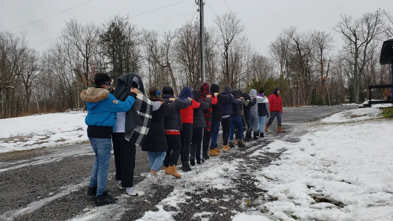 Participants follow one another in a line during an outdoor trust activity